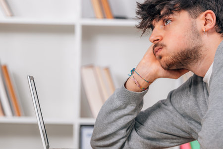 student with computer at desk with tired or exhausted expression
