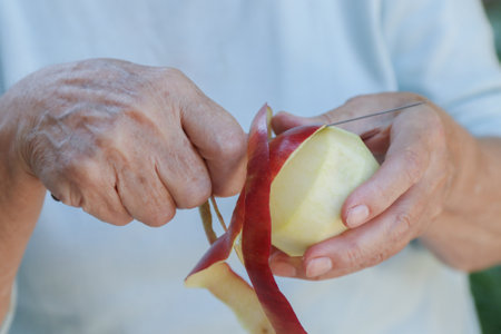 senior hand peeling red apple