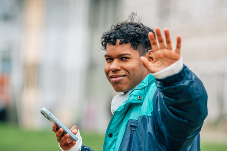 young latino man waving in the streetの写真素材
