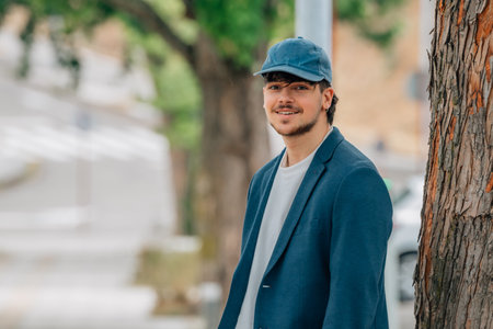 student in a suit and cap on the street smiling