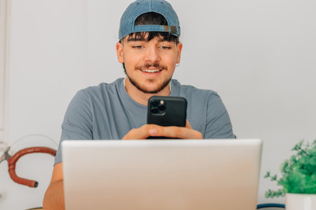 student at desk with mobile phone and laptop
