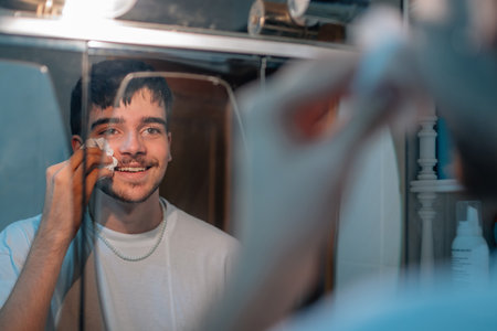 smiling young woman cleaning face in bathroom mirror at homeの写真素材