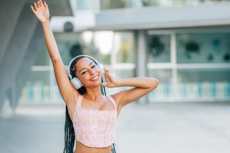 smiling latin girl with headphones on the streetの写真素材
