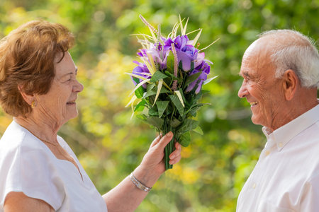 senior couple with bouquet of flowers outdoorsの写真素材