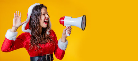 young woman wearing santa claus costume isolated shouting with megaphoneの写真素材