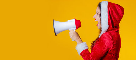 young woman wearing santa claus costume isolated shouting with megaphoneの写真素材