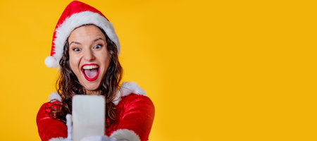 santa claus girl with mobile phone isolated on color backgroundの写真素材