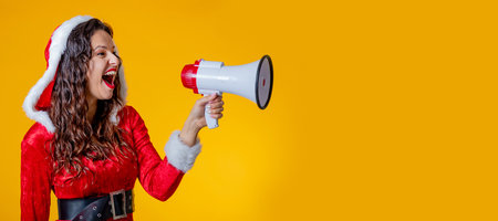 young woman wearing santa claus costume isolated shouting with megaphoneの写真素材