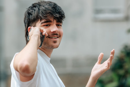 portrait of young man talking on mobile phone on the streetの写真素材