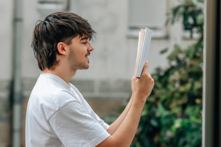 young man with book reading outdoors