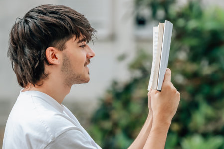young man with book reading outdoorsの写真素材
