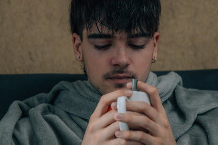 young man at home warm in winter with cupの写真素材