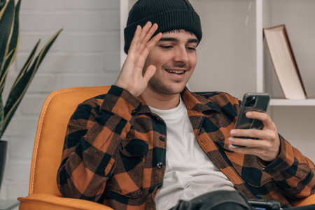 young man at home greeting on mobile phoneの写真素材