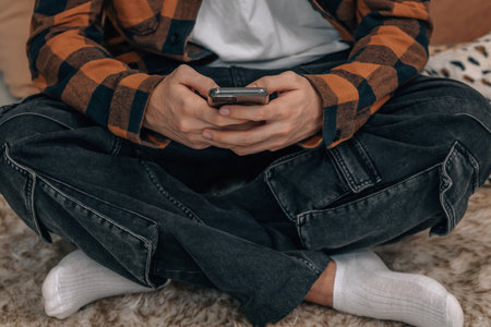 close-up of hands of young man with mobile phone sittingの写真素材