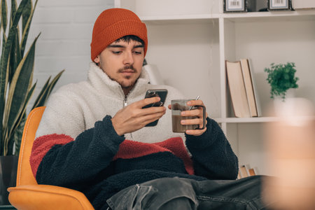 young man at home warm with cup of coffee and mobile phone