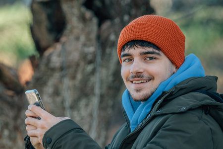 young man bundled up in winter outdoors with mobile phone