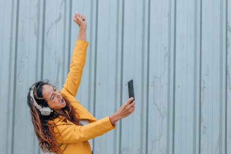 woman with headphones and mobile phone excited with joy on the streetの写真素材