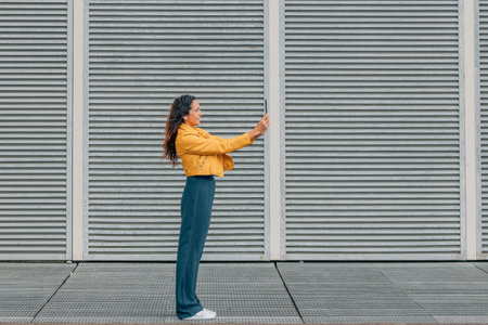 urban woman standing on the street looking at mobile phoneの写真素材