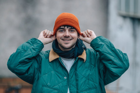 portrait of young man on the street in winter warm and wearing a hat