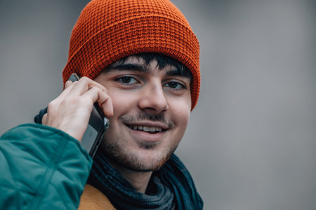 portrait of young man talking on the phone with hat and warm clothes