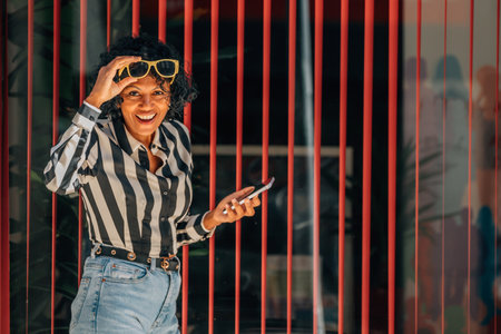 woman looking at camera smiling with sunglasses and mobile phoneの写真素材