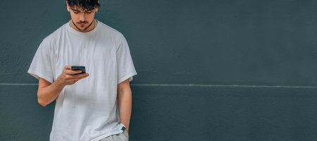 young man or boy looking at his mobile phone on the street