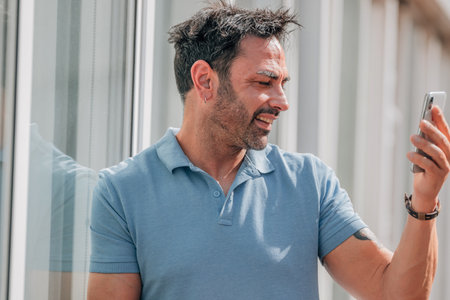 attractive young man with sunglasses looking at his mobile phone on the street outdoorsの写真素材