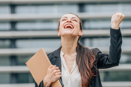 Successful business woman celebrating success. Successful businesswoman with folder in her hands.