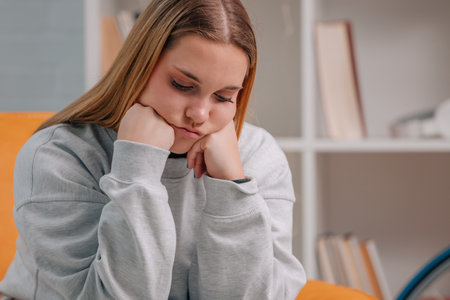 young woman sitting on the sofa at home with sad expressionの写真素材
