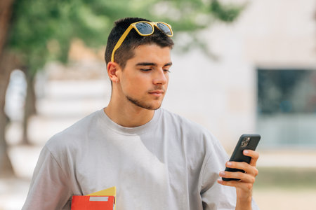 student with books and mobile phone on campus or college outdoorsの写真素材