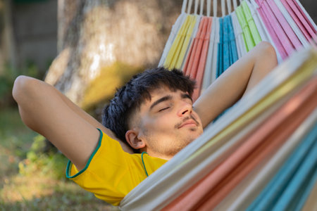 young man in summer sleeping in hammock outdoorsの写真素材