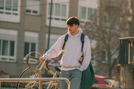 young man or student on the street with vintage bicycle at sunsetの写真素材