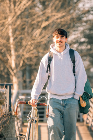 young man or student on the street with vintage bicycle walking, verticalの写真素材