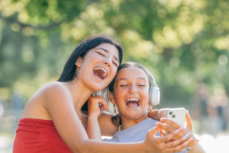 two friends on the street having fun laughing out loud looking at the mobile phone