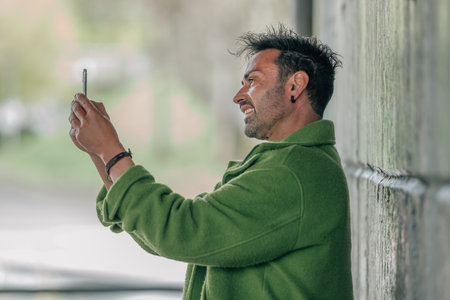 young brunette caucasian man on the street outdoors taking photo or selfie with mobile phone