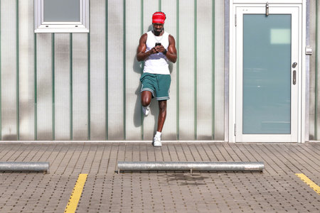 young african man on the street in summer looking at his mobile phoneの写真素材