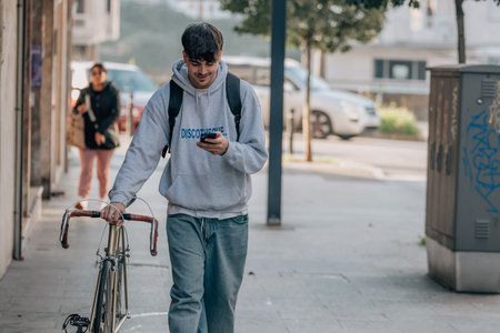 student with mobile phone on the street walking with the vintage bicycleの写真素材