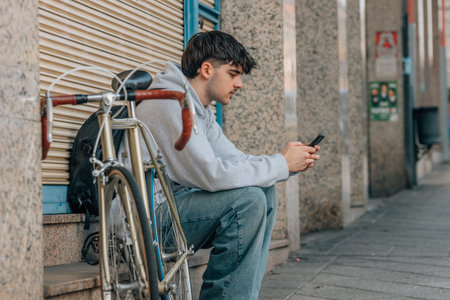 urban cyclist sitting on the street with mobile phone