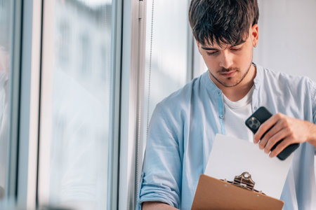 young man or student with mobile phone reviewing documentation