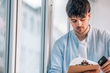 young man or student with mobile phone reviewing documentation
