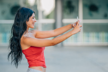 young latin girl or woman with summer clothes looking at her mobile phone or smartphoneの写真素材