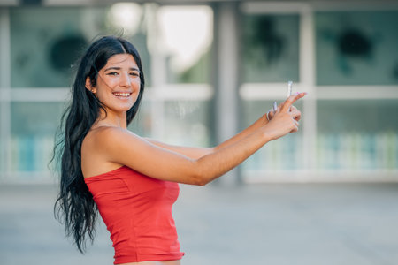 young latin girl or woman with summer clothes looking at her mobile phone or smartphoneの写真素材