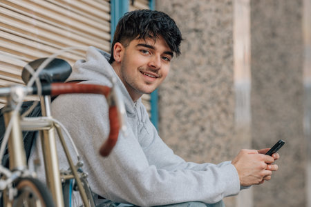 urban cyclist sitting on the street with mobile phoneの写真素材