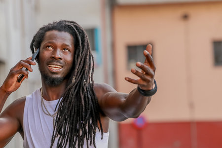 young man with afro hair or dreadlocks talking on mobile phone on the streetの写真素材