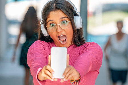 girl with surprise gesture on the street with headphones and mobile phone