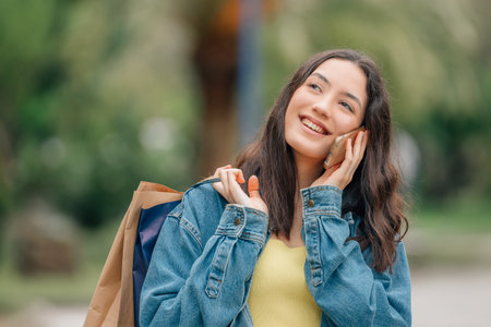 girl on the street talking on the mobile phone with shopping or shopping bagsの写真素材