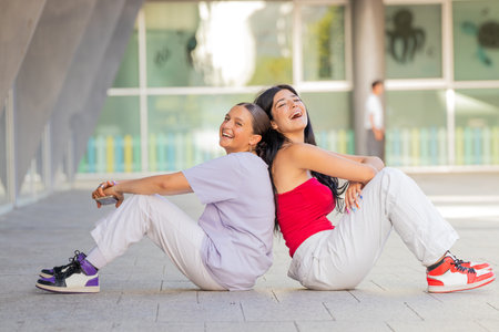 friends sitting on the street smiling out loudの写真素材