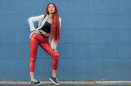 redhead funky urban hipster girl posing on the street isolated on blue wall backgroundの写真素材