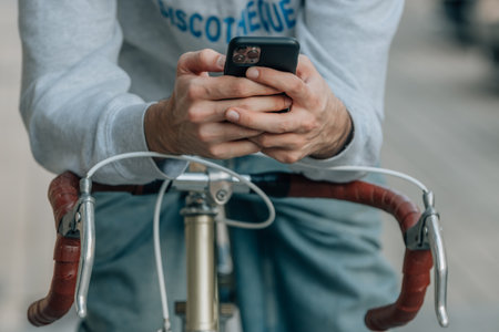 close-up of hands using mobile phone or smartphone on vintage bicycleの写真素材