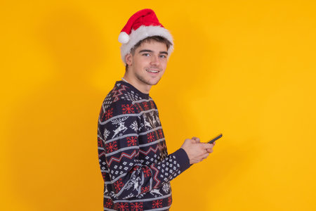 isolated young man with santa claus hat and mobile phoneの写真素材